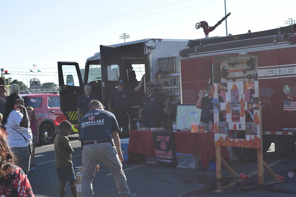 A Moses Lake firefighter prepares a hose for children to spray at a target for a game during Tuesday’s National Night Out event.