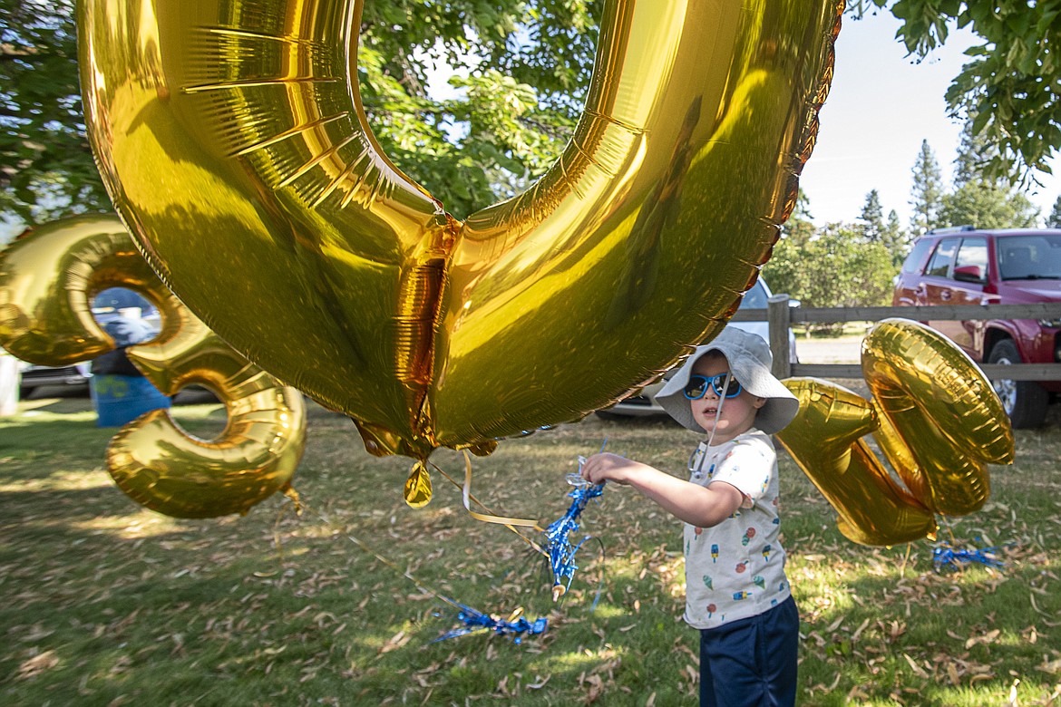 Three-year-old Max Miller plays with the Class of 2013's reunion decorations at the Wildcat Endowment Auction in Marantette Park in Columbia Falls on Friday, July 28.