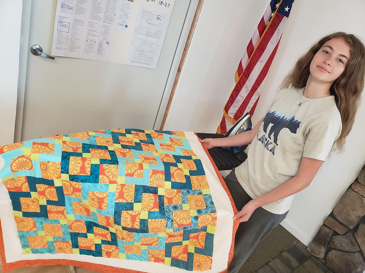 Ireland Clark brings her quilt to an ironing board in the Coeur d'Alene Shrine Club Event Center. Once it's ironed, she'll sew on the binding to finish it.