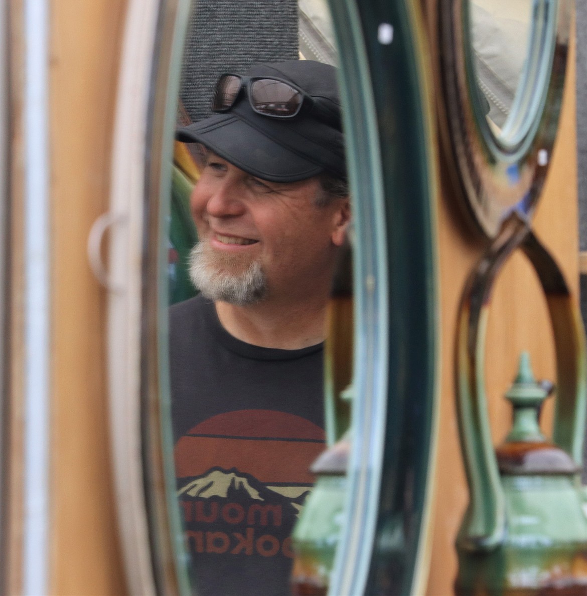 James Diem is reflected in a mirror at his booth at Art on the Green on Friday.