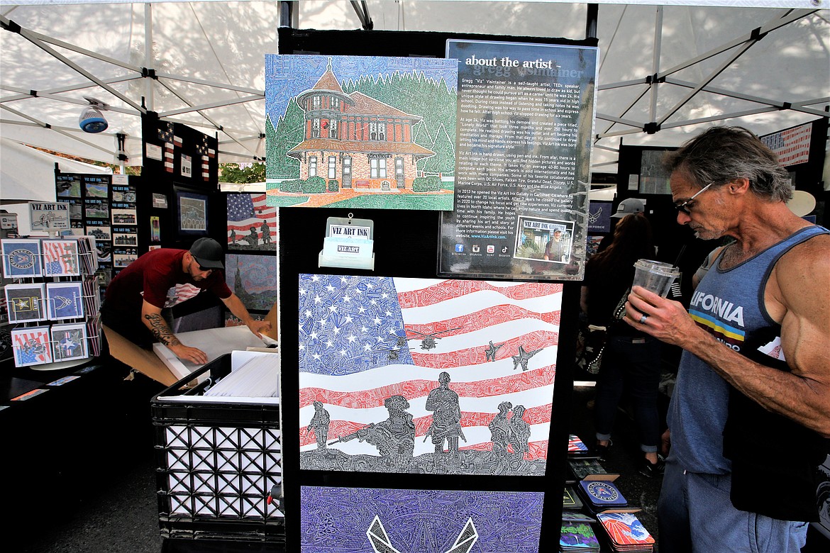Gregg "Viz" Visintainer, left, wraps up artwork while a customer looks over his work during the Street Fair on Friday.