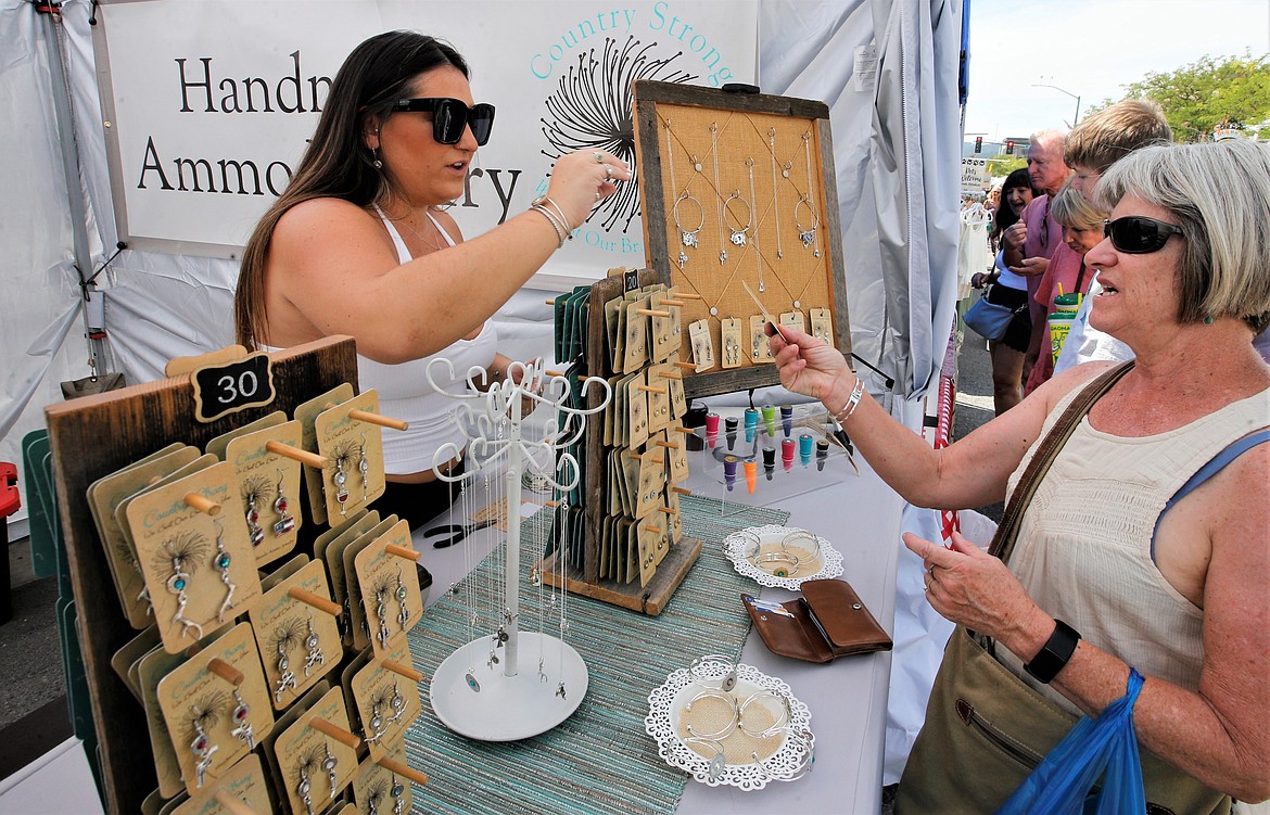 Taylor Meserve helps a customer at her booth offering handmade ammo jewelry at the Street Fair.