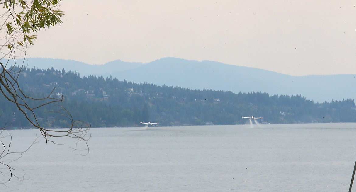 Single-engine airtankers scoop water from Hayden Lake as efforts are underway Friday to control the Ridge Creek Fire.