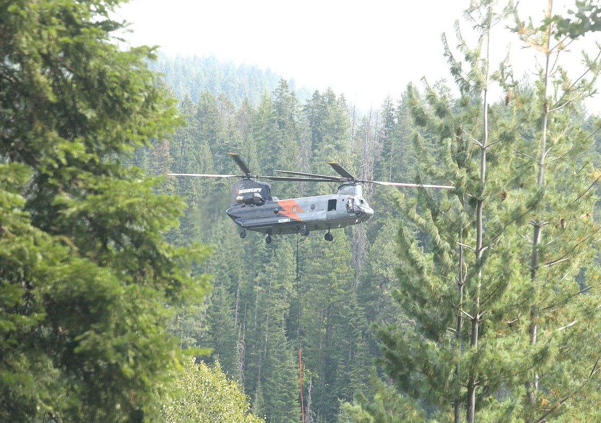 A helicopter is seen above the trees as efforts are underway Friday to control the Ridge Creek Fire burning on national forest land north of Hayden Creek Road in the Ridge Creek drainage.