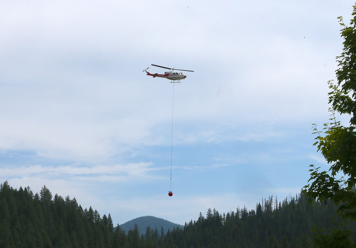 A helicopter moves a bucket of water over the trees Friday to the Ridge Creek Fire above Hayden Lake.