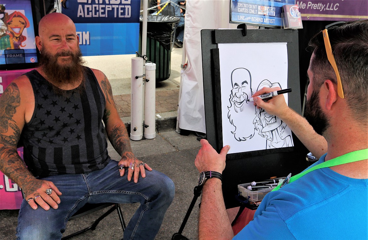 Dexter Rothschild draws Tom Smith during the Street Fair on Friday.
