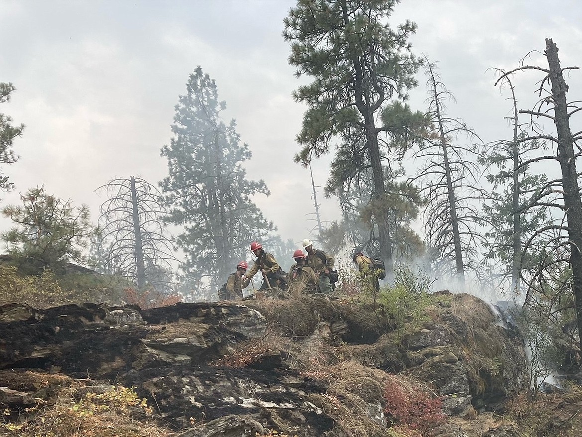 Fire crews fight the Parkway Fire located in in a steep, heavily timbered above the Spokane River, near the dam at Post Falls.