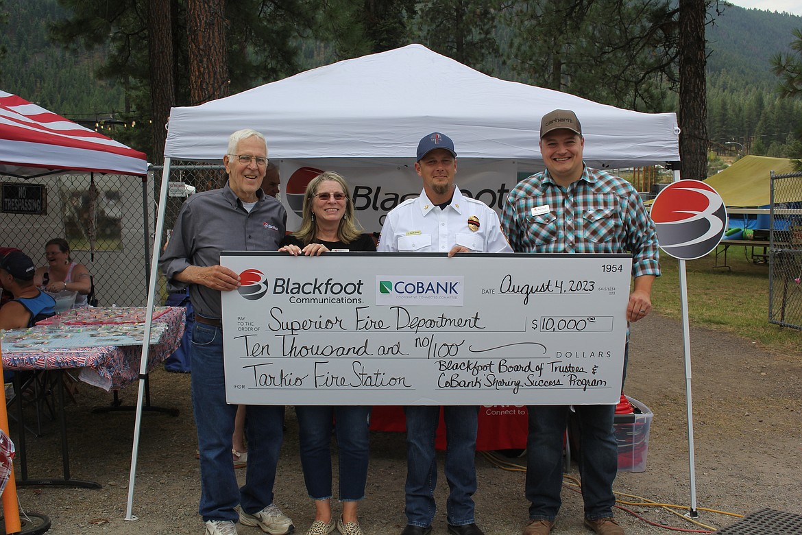 Geoff Wilson, Blackfoot Communications Board of Directors, left, along with Marilee Klaudt and Chris Laslovich, employees with Blackfoot, surround Scott Dodd the Chief of the Superior Volunteer Fire Department. Blackfoot Communications and CoBank each gave $5,000 to help with the needed supplies at the Tarkio Fire Station which is temporarily housed on private property in Nemote Creek until the new station is built. (Monte Turner/Mineral Independent)