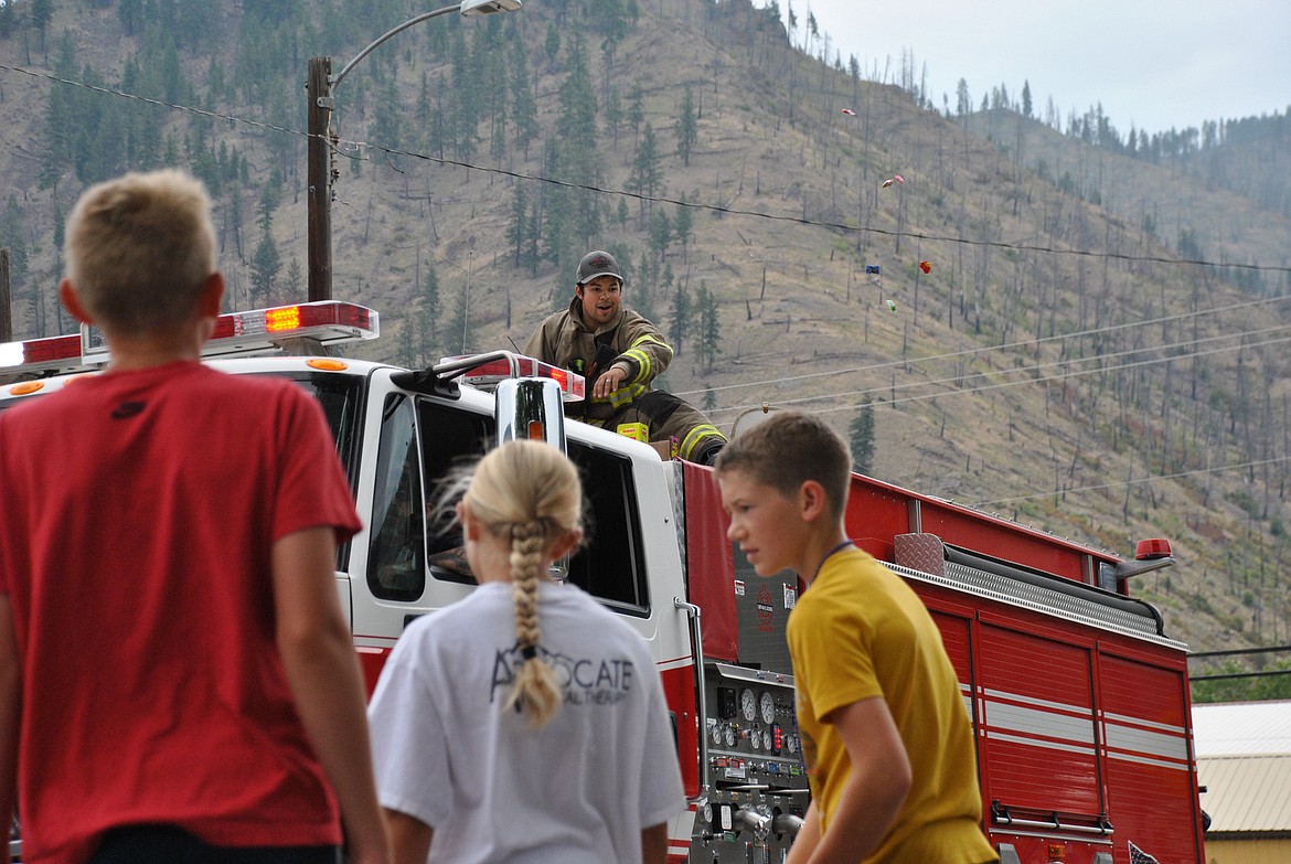 Deputy Chief of the Superior Volunteer Fire Department, Josh Pecora, slings a handful of candy to the children. (Mineral Independent/Amy Quinlivan)