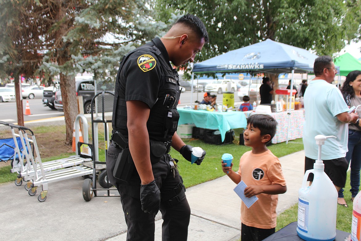 Mattawa Officer Edgar Villa, left and Joao Garcia have a chat over snow cones at National Night Out Friday.