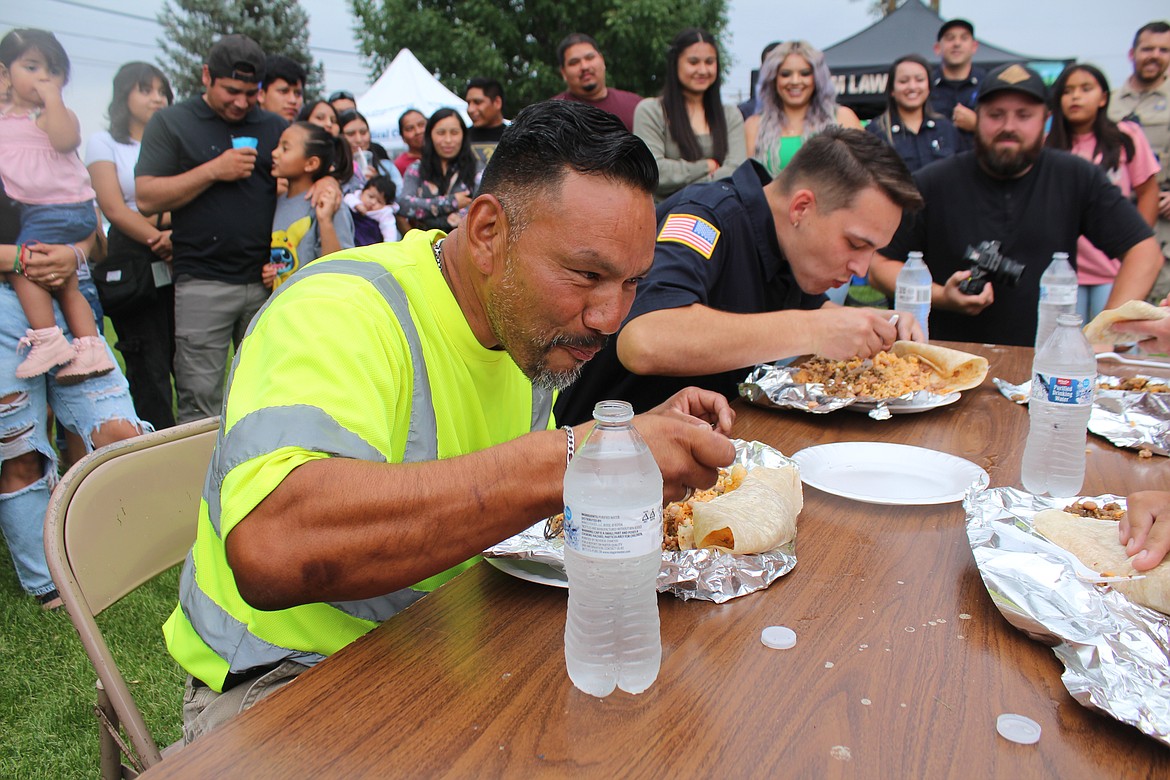 Albert Reyes works through a three-pound burrito in the burrito-eating contest during the Mattawa Police Department’s National Night Out. The eventual champion, Greg Miller of Grant County Fire District 8, is in the background.