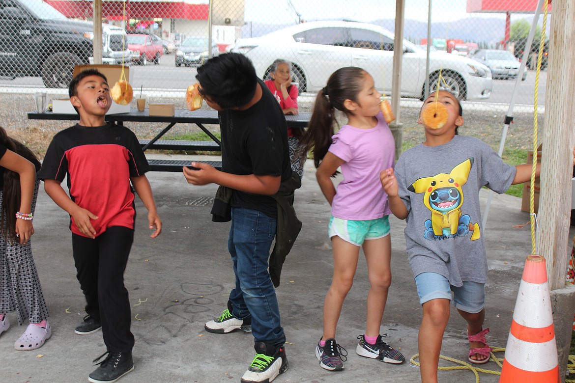 Children try their hand - or rather, no hands - at the doughnut-eating contest.