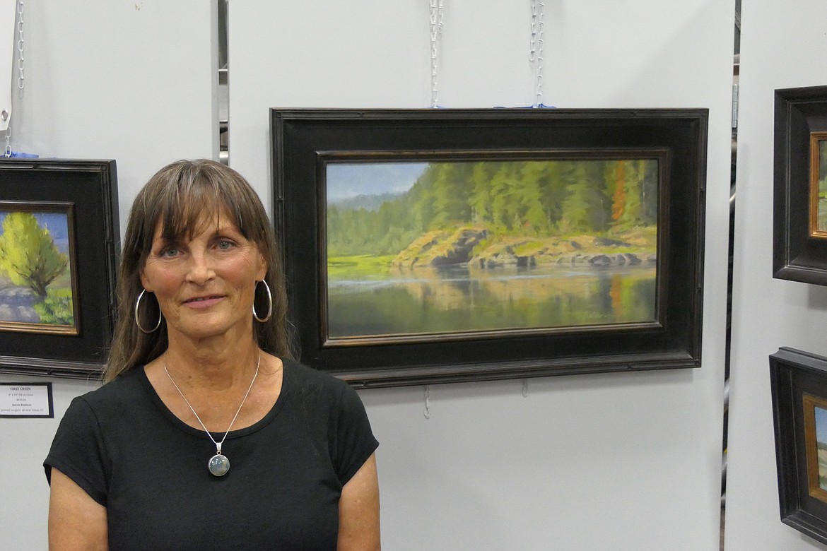 Thompson Falls artist Karrie Baldwin stands next to some of the landscape paintings she has created and brought to the Paradise Center this past weekend. (Chuck Bandel/VP-MI)