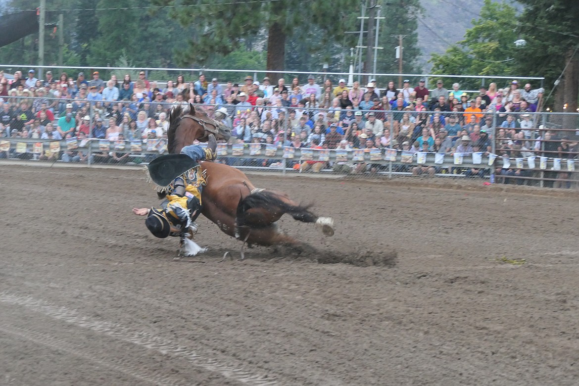 A 51-year-old cowboy and the saddle bronc he was riding tumble to the dirt during Saturday's final go-round of the Superior Lions Club Rodeo, part of the Mineral County Fair in Superior.  The cowboy sustained wrist injury during the ride. (Chuck Bandel/VP-MI)