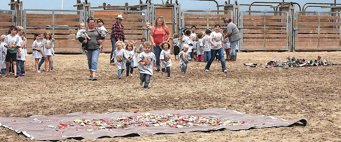 The youngest kids at the Kiddy/Slicker Rodeo make a run for the candy. Kids grabbed candy, and then their "adult" found them and retrieved their shoes from the shoe heap before running for the judge. (Berl Tiskus/Leader0