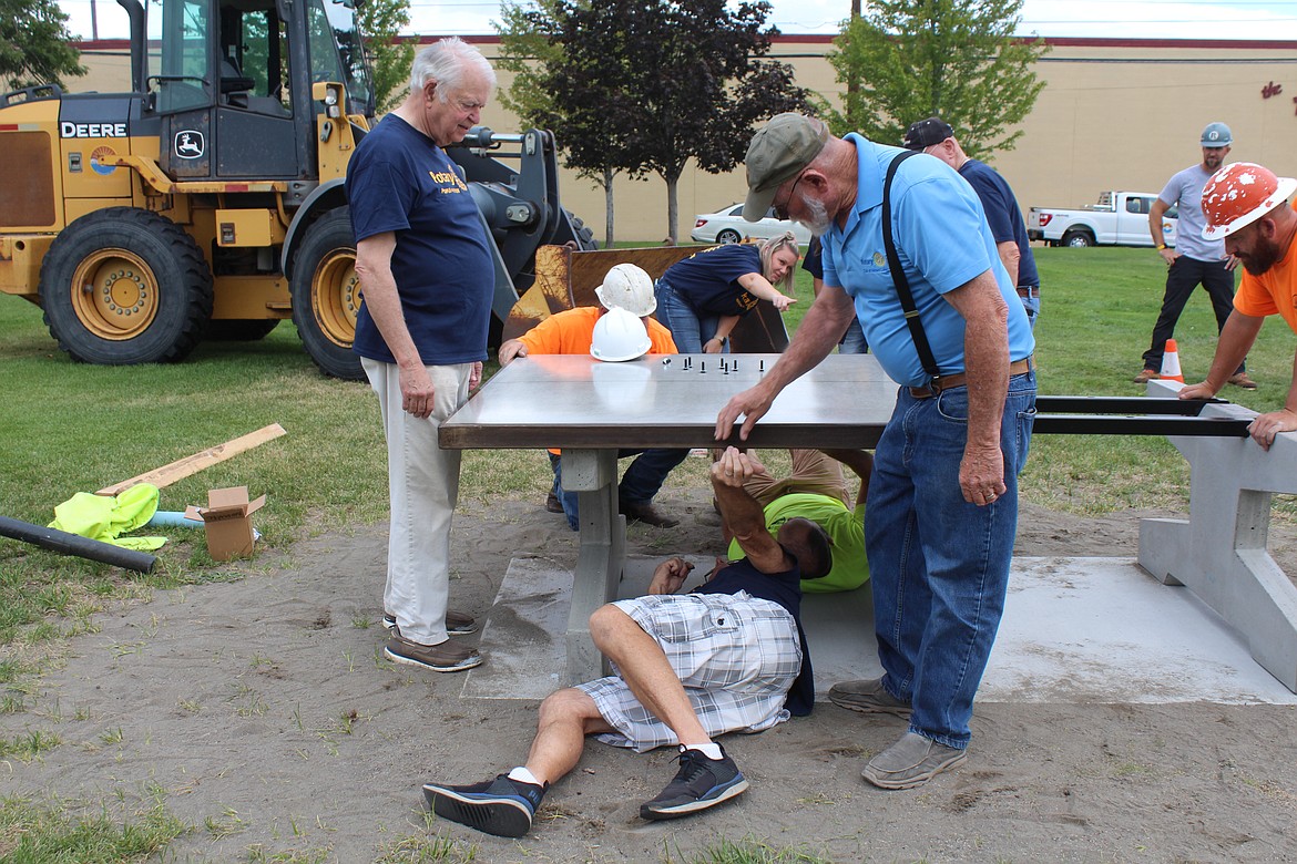 Norm Benson of the Moses Lake Rotary, right, hands a bolt to fellow Rotarian Gary Ash, under the table. Rotary members and city crews installed a new ping-pong game, pictured, a chess/checkers game and bean bag toss games in a Moses Lake park Wednesday morning.