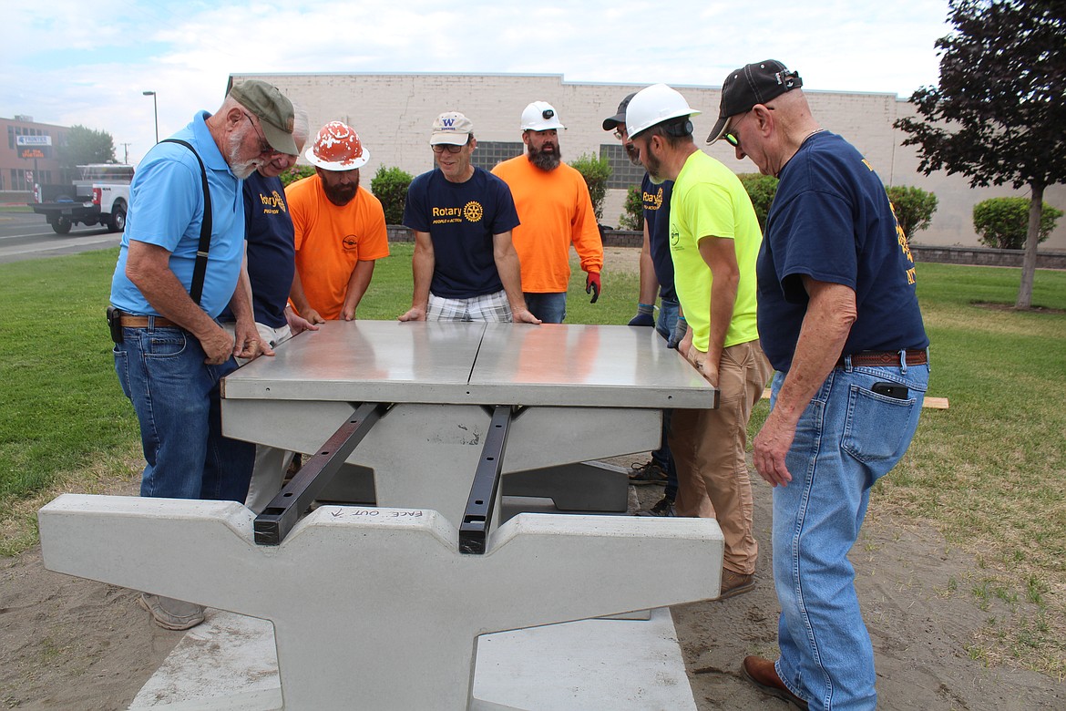 Moses Lake Rotary members and city workers move the polished concrete top on a new ping pong game into place in Carl T. Ahlers Memorial Park Wednesday.