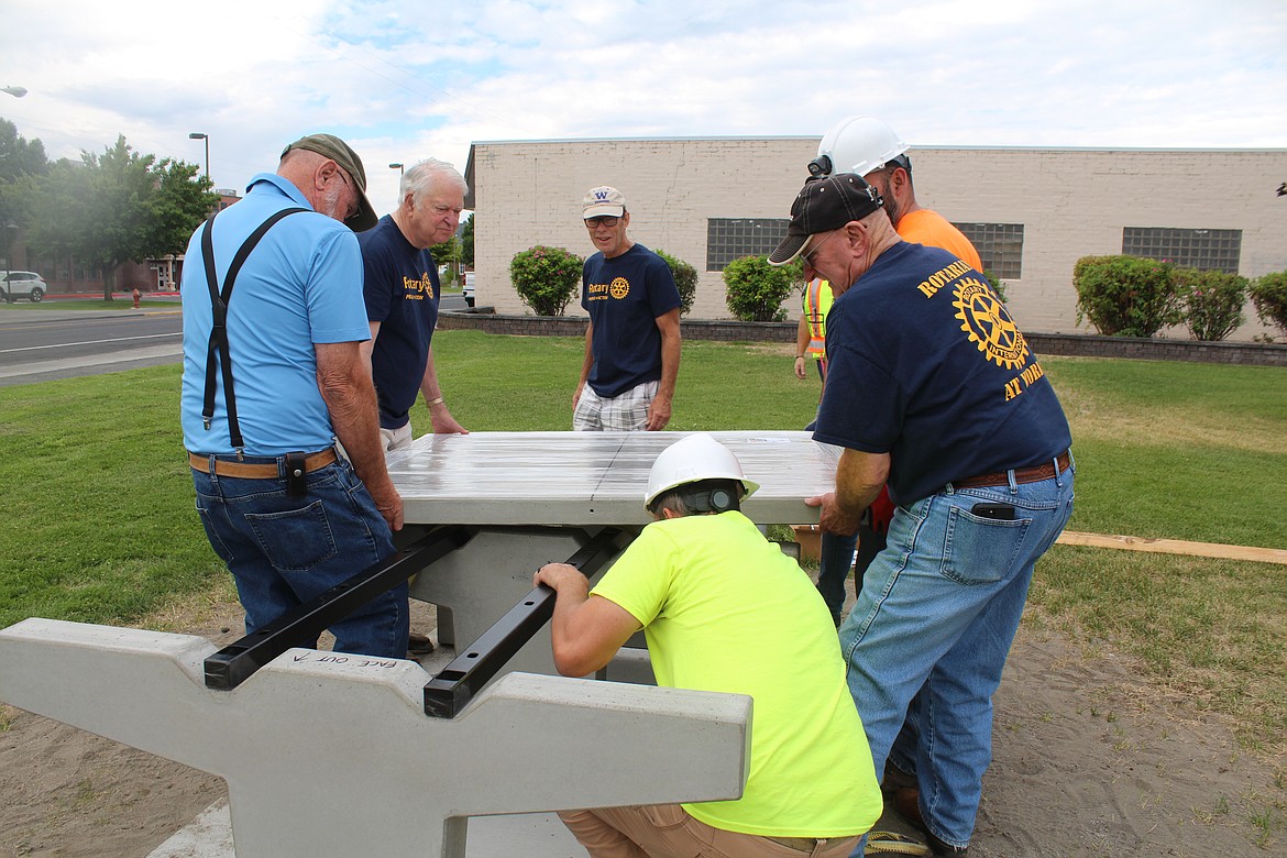 A ping pong table top is maneuvered into place in Ahlers Memorial Park.