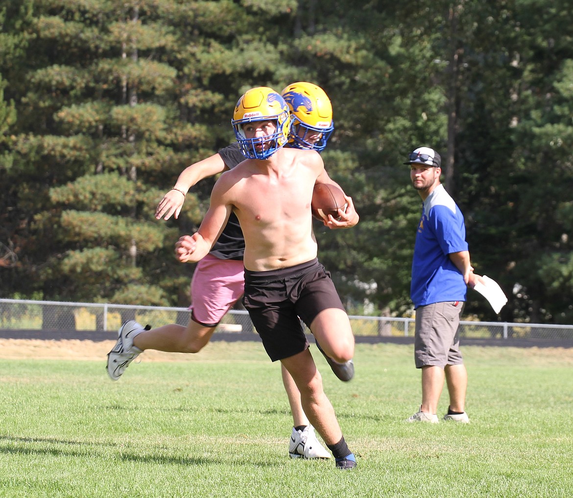 Senior Ethan Howard makes a move and passes a defender during a practice play as first-year head coach Patrick Young watches closely in the background.