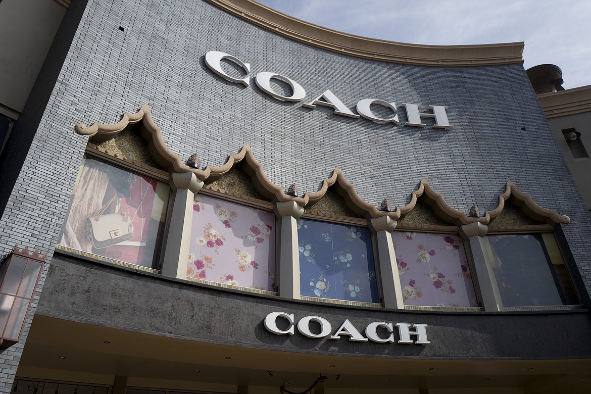 FILE - This photo shows a Coach retail shop at the Citadel Outlets in Commerce, Calif., on May 3, 2019. Tapestry, parent company of luxury handbag and accessories retailer Coach, is buying the owner of fashion brands including Michael Kors, Versace and Jimmy Choo, Capri Holdings. The approximately $8.5 billion deal puts Tapestry in a better position to take on its big European fashion rivals. (AP Photo/Richard Vogel, File)