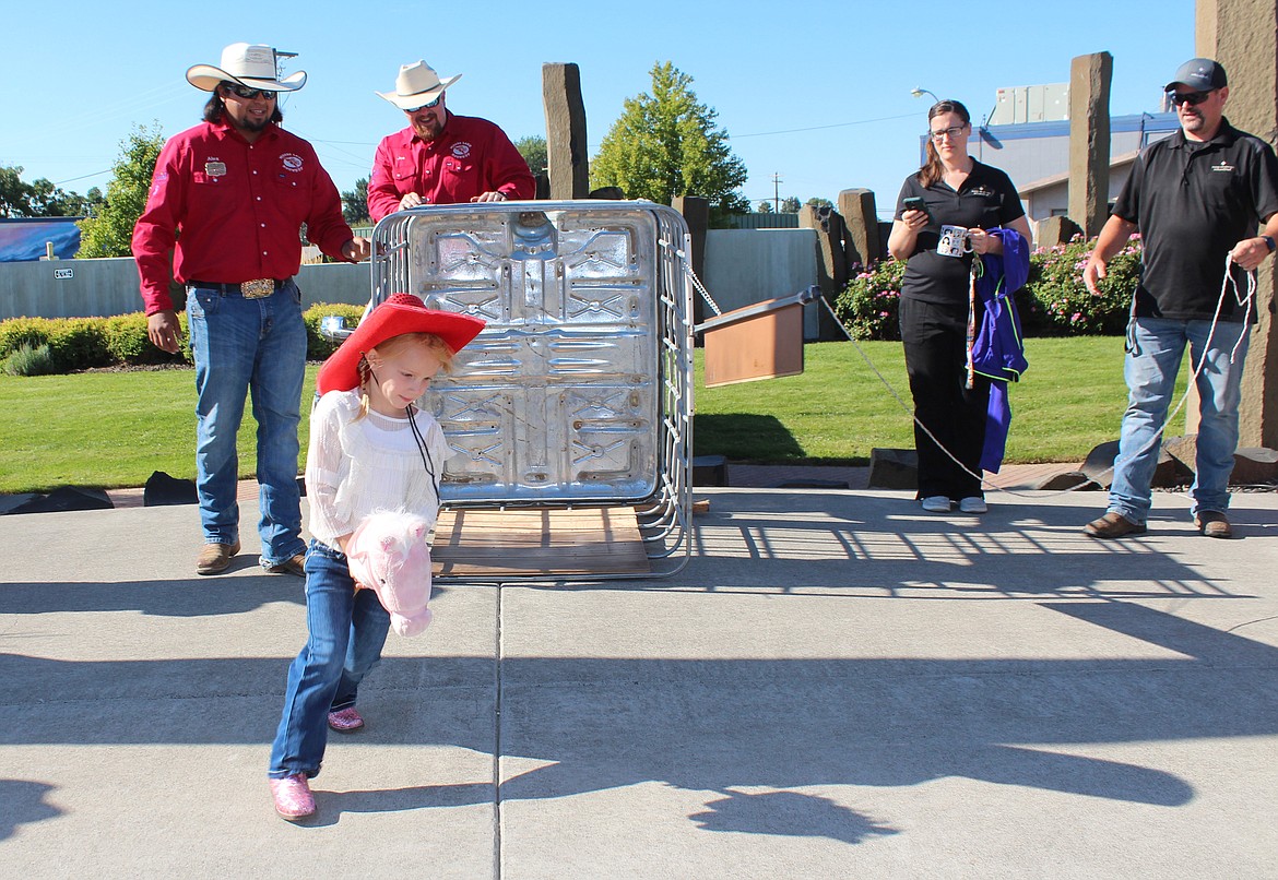 With red hat, pink boots and pink horse, a bronc rider takes to the arena at the Pee Wee Rodeo.