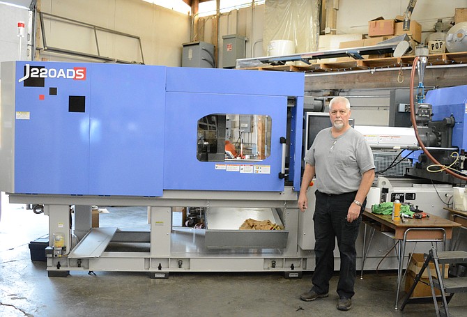 Bruce Rumpel stands in front of one of the new electric machines at Kellogg Plastics in Smelterville. The company currently has a staff of five and creates plastics through injection mold machinery.