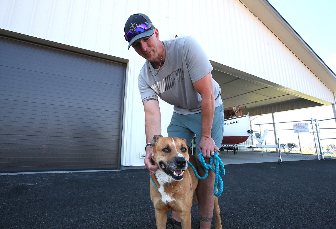 Canine trainer John Huss stands with his legs around George as he works with him Friday at Companions Animal Center.