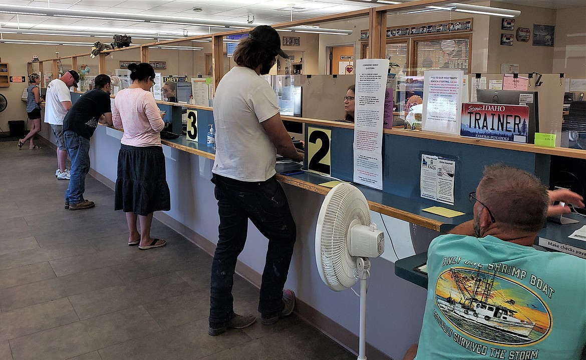 People wait at the counter of the Driver's License Office in Coeur d'Alene on Friday.