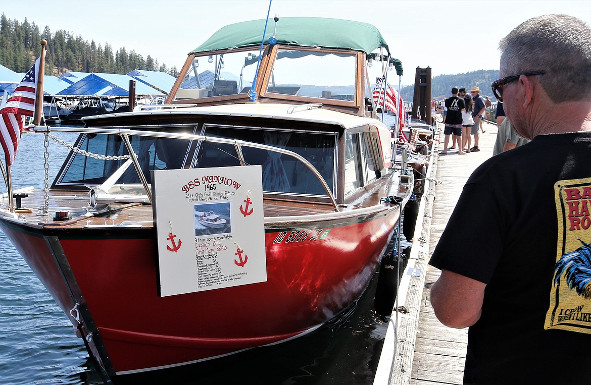 A visitor looks over the "BSS Minnow" in the Coeur d'Alene Antique and Classic Boat Festival at The Boardwalk on Saturday.