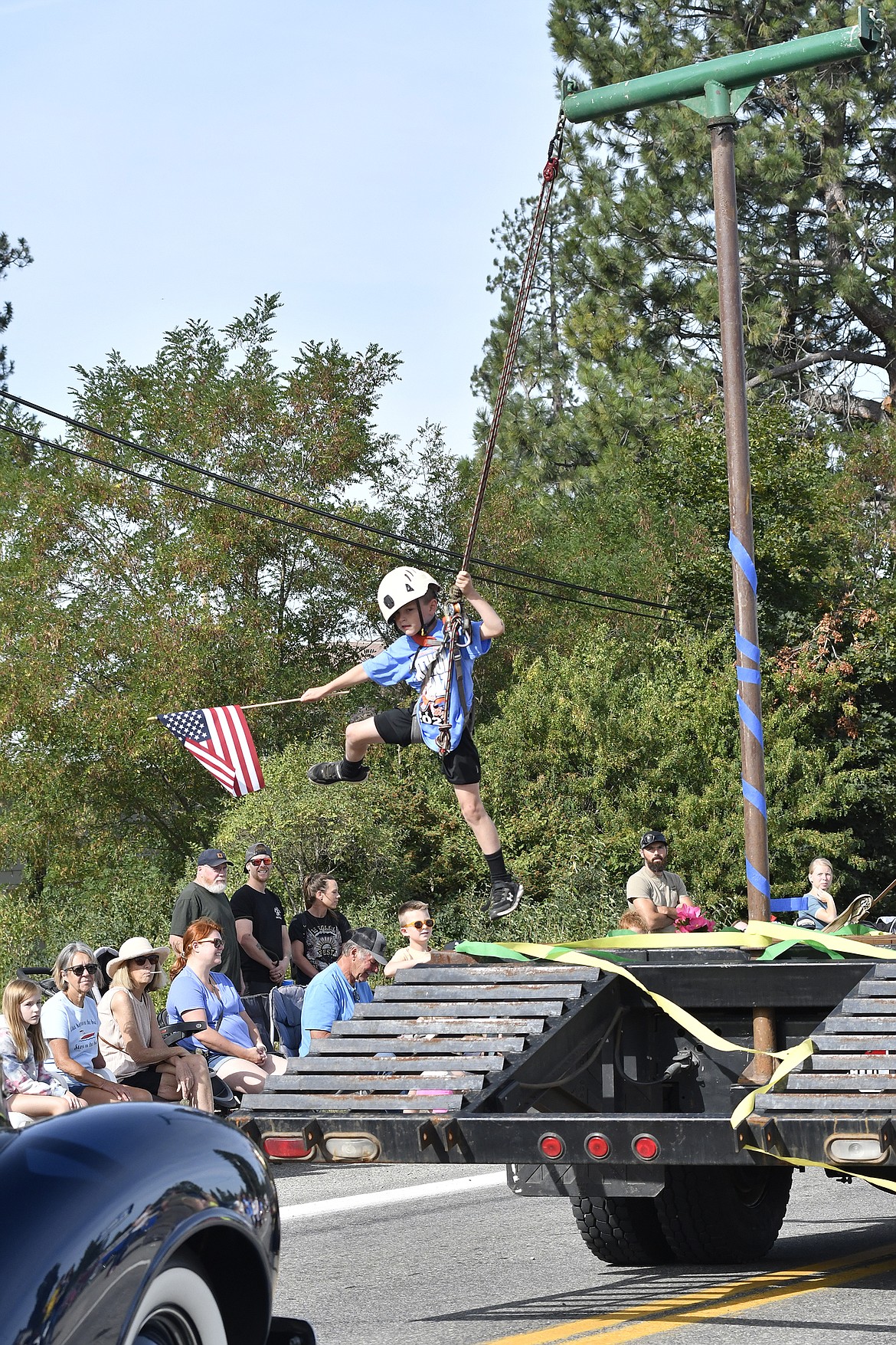 A boy leaps and swings in circles around the back of a float during the Athol Daze Parade, Saturday.