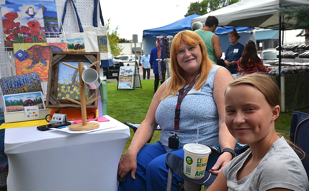 Andrea Johnson shared her paintings at Saturday's Courthouse Art Festival while her granddaughter, Scarlet, helped out. (Kristi Niemeyer/Leader)