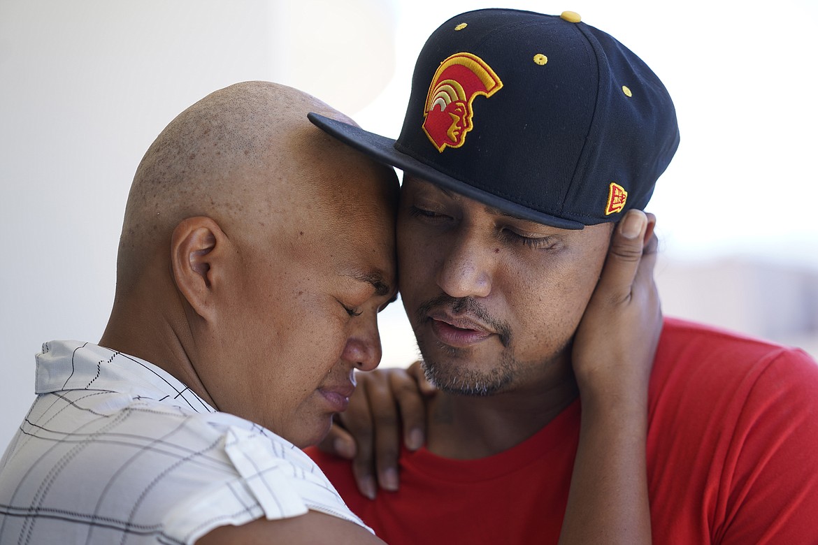 JP Mayoga, right, a chef at the Westin Maui, Kaanapali, and his wife, Makalea Ahhee, hug on their balcony at the hotel and resort, Sunday, Aug. 13, 2023, near Lahaina, Hawaii. About 200 employees are living there with their families. Officials urge tourists to avoid traveling to Maui as many hotels prepare to house evacuees and first responders on the island where a wildfire demolished a historic town and killed dozens of people. (AP Photo/Rick Bowmer)