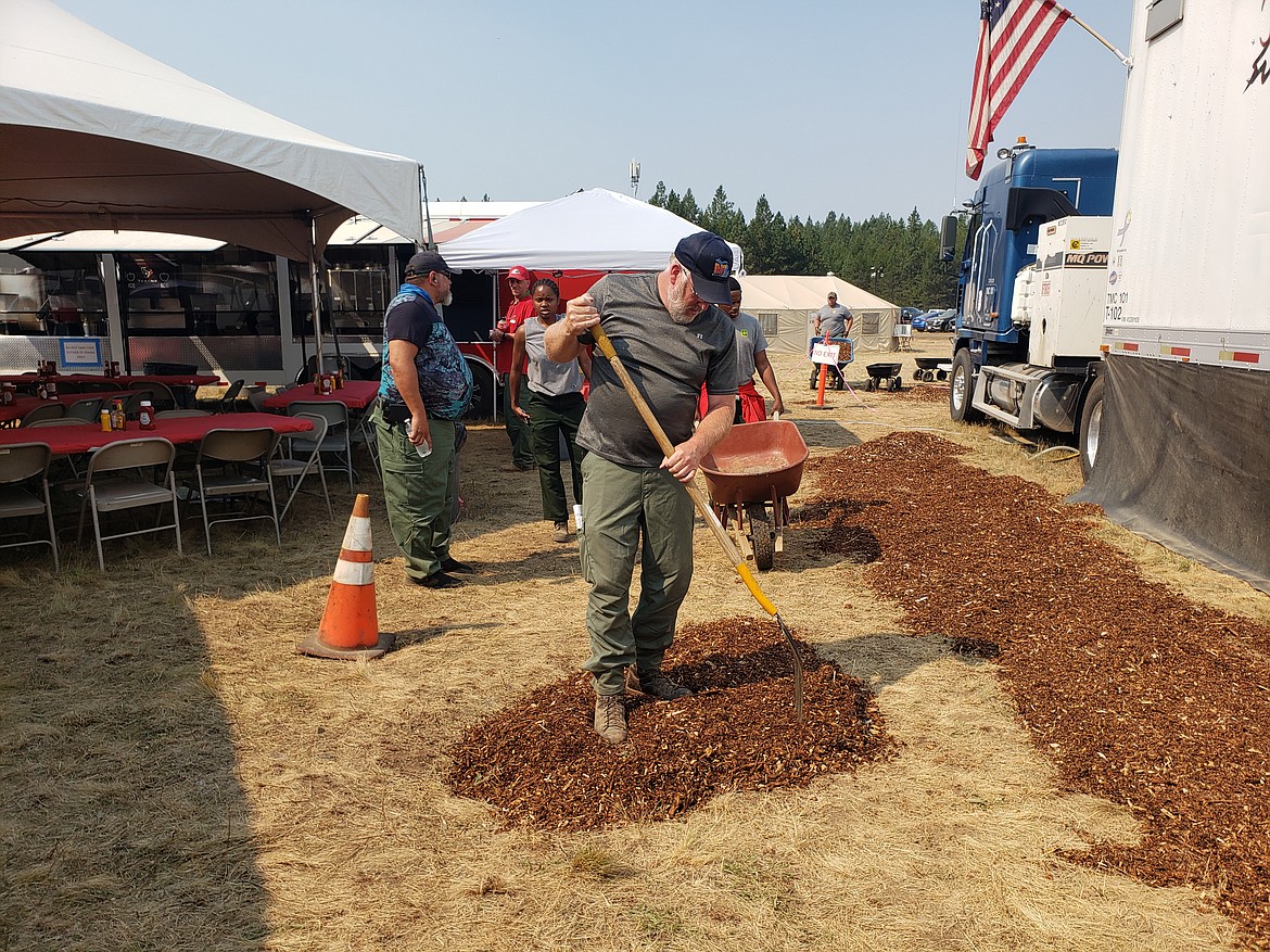 Maintenance crews spread damp wood chips around the mess hall to keep dust down at the fire camp. The chips also fill in holes in the ground that are unsafe for crews.