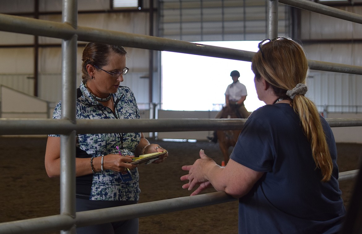 English Equitation Judge Heidi Bach looks over notes before the judging panel determines the ribbons to award at the English Equitation event at the Grant County Fair. Bach judges multiple horsemanship events at the fair.