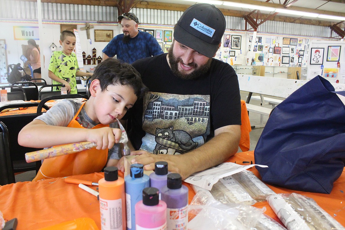 Theo Zollinger, 7, builds a tool caddy with the help of his dad Garrett Zollinger Wednesday at the Kids Workshop at the Grant County Fair.