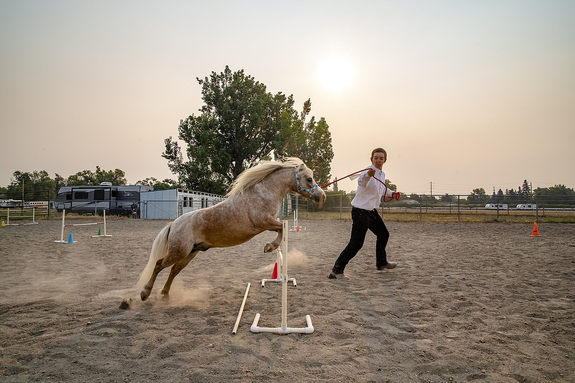 Chaise Piliey leads his horse through a jump at Flathead County Fairgrounds on Thursday, Aug. 17. (Avery Howe/Hungry Horse News)