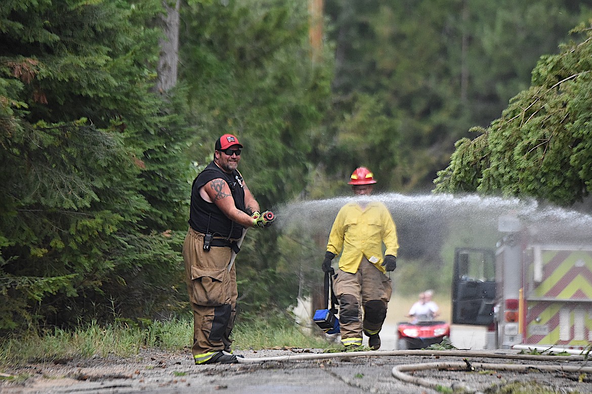 A Lincoln County Rural Fire District No. 1 firefighter douses a wildfire on Bobtail Road north of Libby Friday afternoon. A tree that downed a power line caused the blaze. (Scott Shindledecker/The Western News)