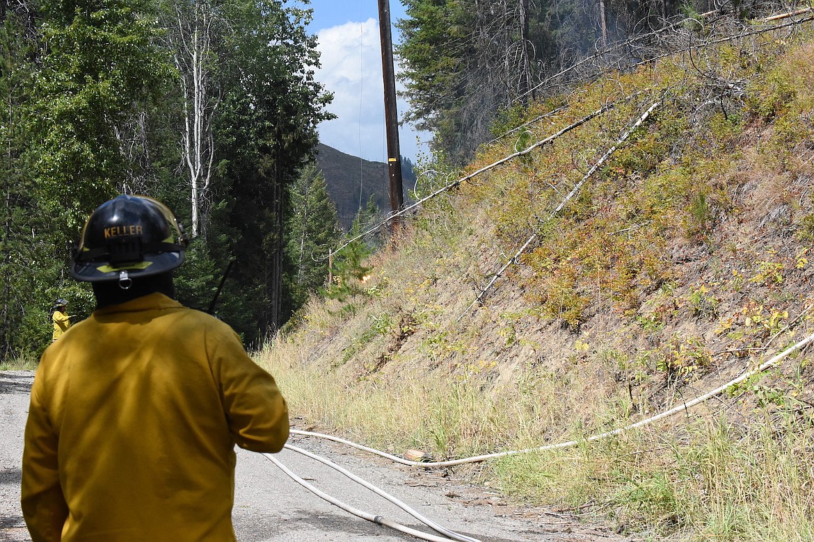 Lincoln County Rural Fire District No. 1 volunteer Kyle Keller watches as a downed power line arcs at the scene of a wildfire on Bobtail Road north of Libby Friday afternoon. A tree that downed the line caused the blaze. (Scott Shindledecker/The Western News)