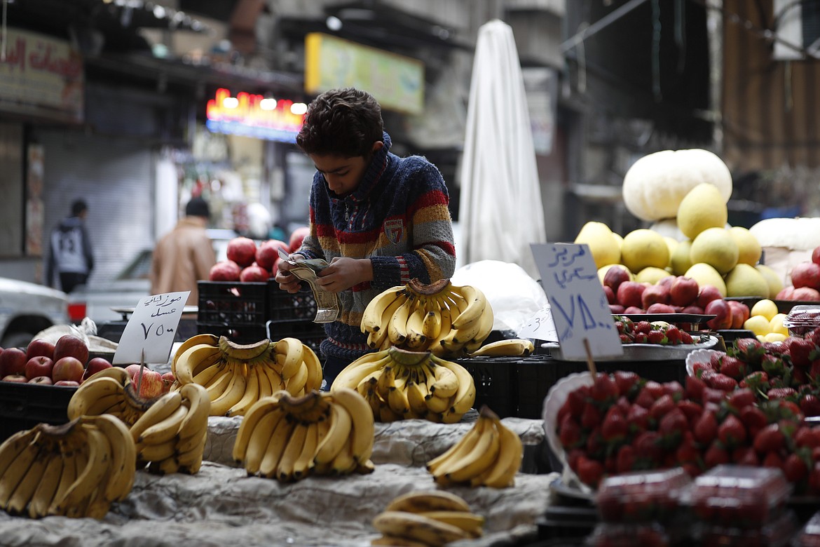 FILE - Shopkeeper waits for customers in Damascus, Syria, on Dec. 15, 2022. Syria’s president early Wednesday Aug. 16, 2023 doubled public servant and retirees wages and pensions as the war-torn country’s national currency spiraled further downwards, reaching a new low for the year. (AP Photo/Omar Sanadiki, File)