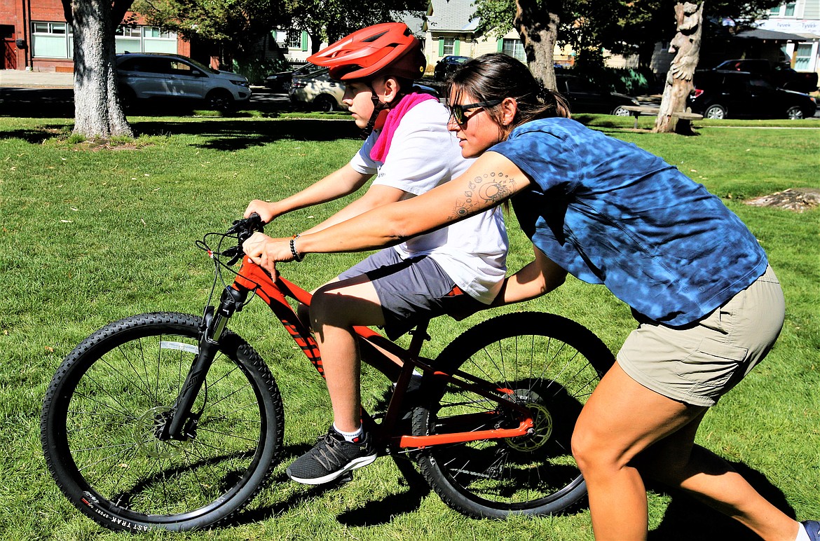 Alli Williams helps Skyler Andersen ride a bike at G.O. Phippeny Park on Friday.