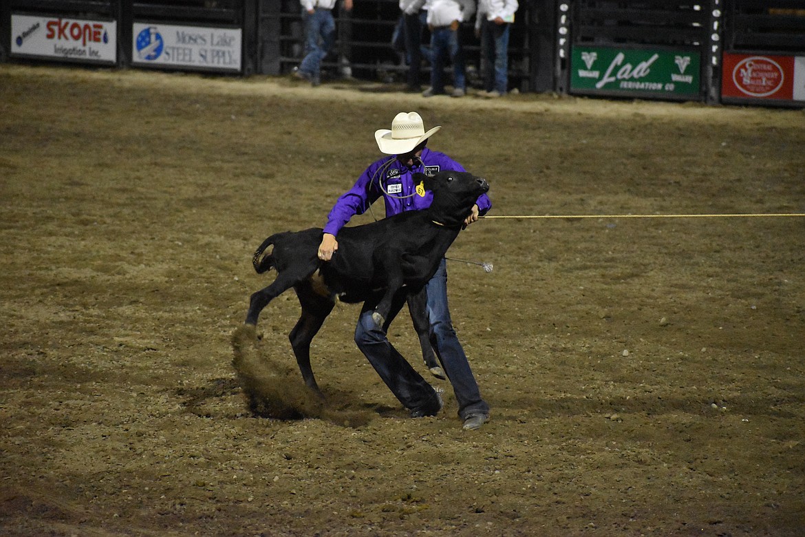 Tie-down roper Kass Newman of Moses Lake picks up a steer before tying its legs on Thursday.