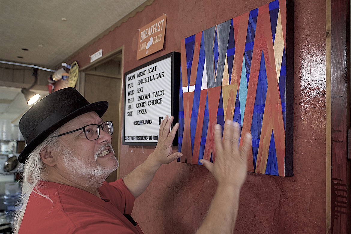 Frank Finley displays one of his paintings in his coffee shop, 32 Cuppa Java. He said he loves using metallic paints for his work. (Max Dupras/Leader)