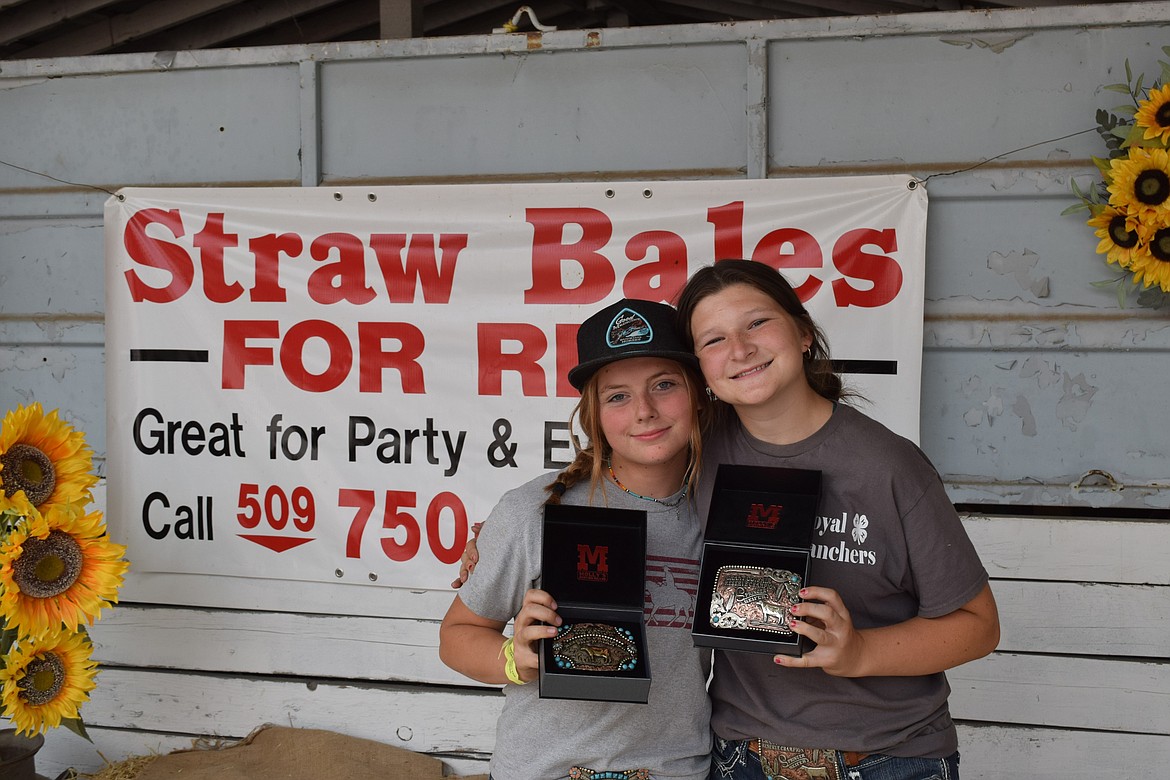 Ashley Zagelow, left, and Haidyn Sutor hold their decorative belt buckle awards outside of the Grant County Fairgrounds Sale Barn after Saturday afternoon’s Livestock Awards at the fair.