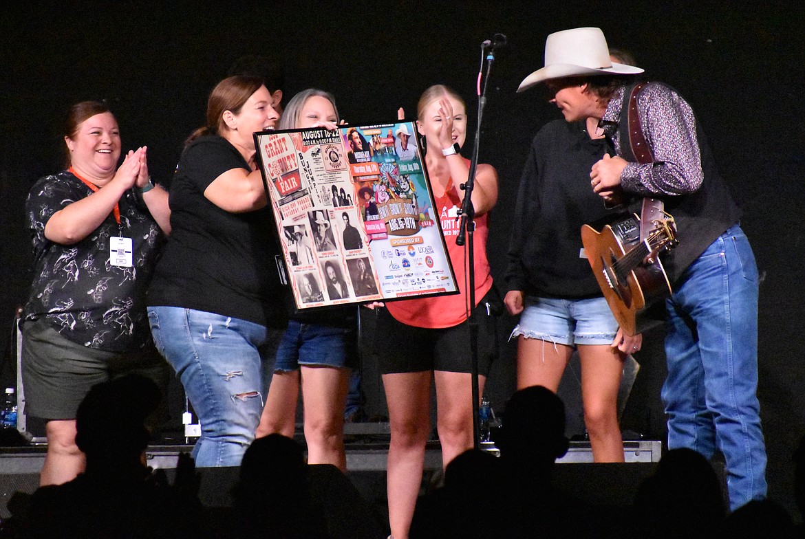 Grant County Fairgrounds staffer Darci Homesley presents Ned LeDoux with a framed copy of the fair posters from his performance and his father’s, 31 years earlier to the day.
