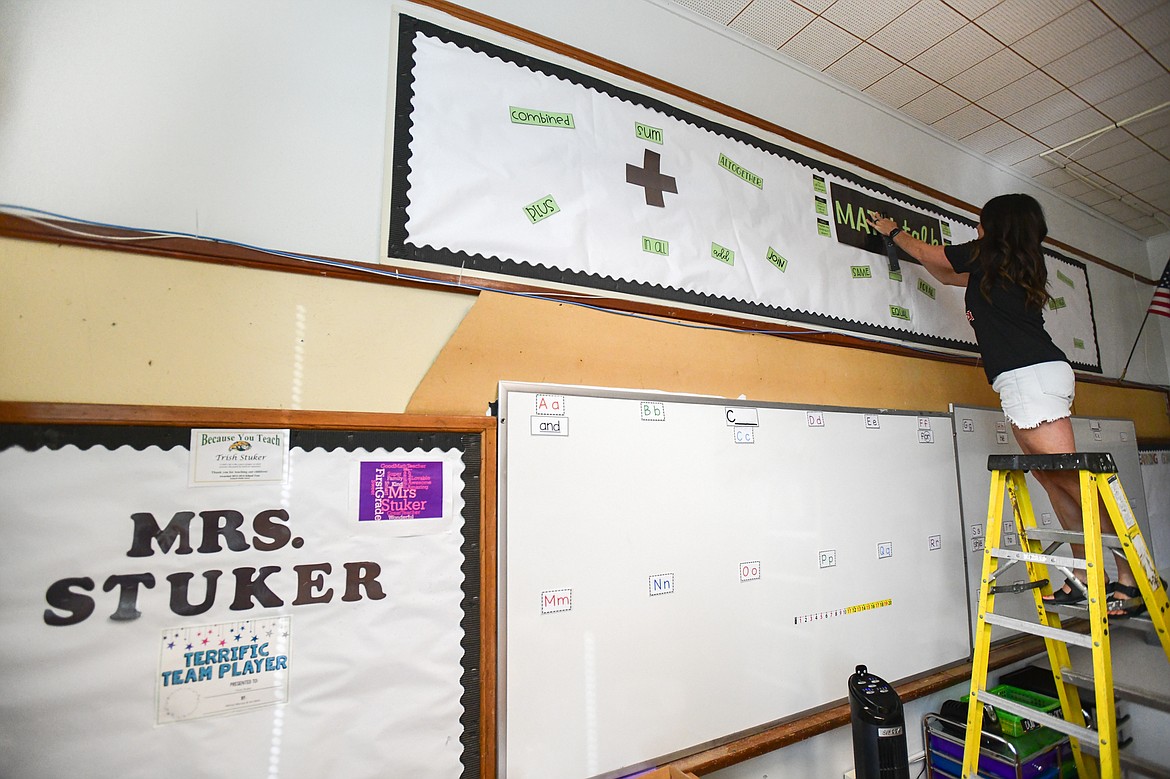 First-grade teacher Tricia Stuker hangs a math table bulletin board in her classroom at Russell Elementary School in Kalispell on Tuesday, Aug. 22. (Casey Kreider/Daily Inter Lake)