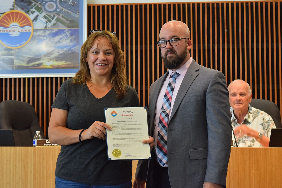 Columbia Basin Cancer Foundation Executive Director Angel Ledesma, left, stands next to Mayor Don Myers, right, while holding a proclamation from the city of Moses Lake declaring September Childhood Cancer Awareness Month.