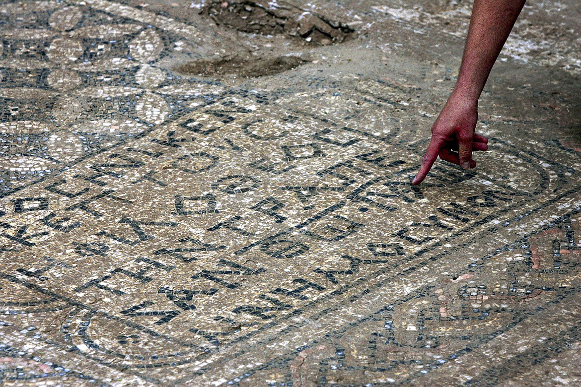 An Israeli archaeologist points at a nearly 1,800-year-old decorated floor from an early Christian prayer hall that Israeli archaeologists discovered in 2005. Israeli officials are considering uprooting the mosaic and loaning it to the controversial Museum of the Bible in Washington D.C.