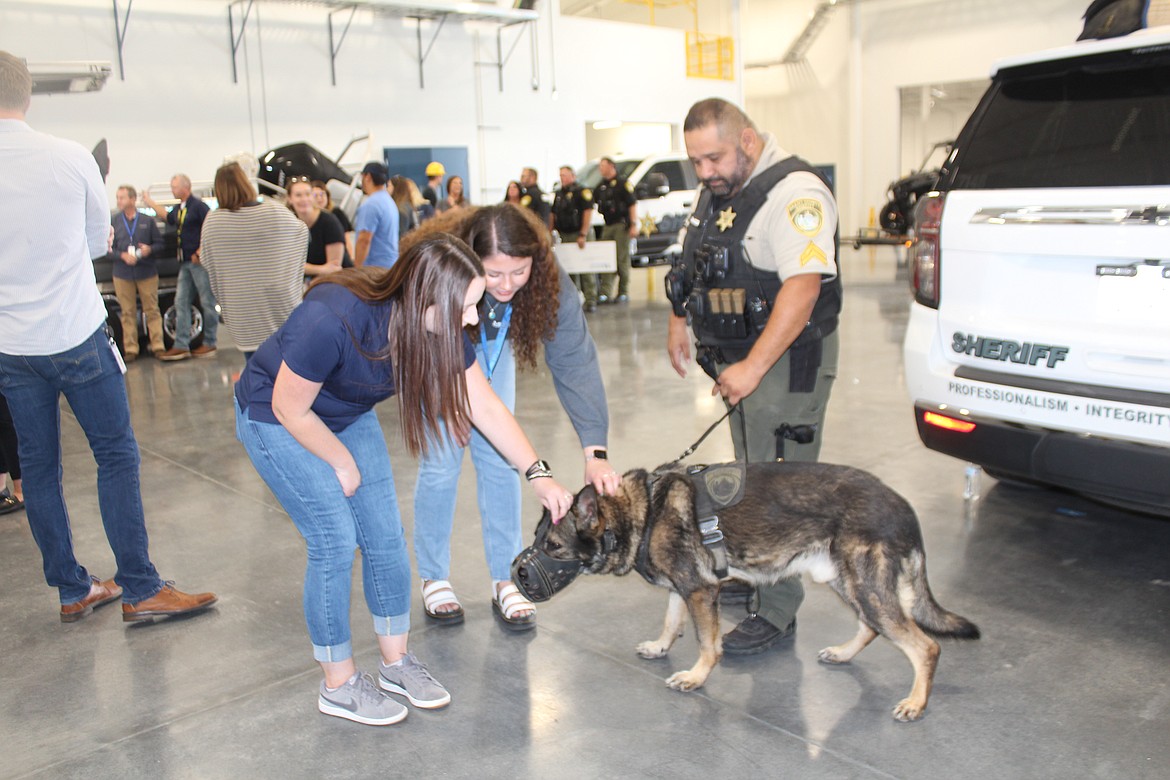 Two Moses Lake Industries employees give some attention to K-9 Hawk, in the company of his handler Dave DeLaRosa, left.