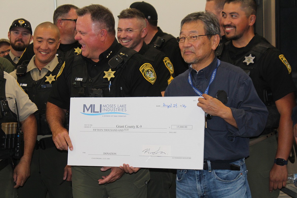 Grant County Sheriff Joe Kriete, left, accepts a check for $15,000 from Moses Lake Industries President Hiroyuki Era, right.