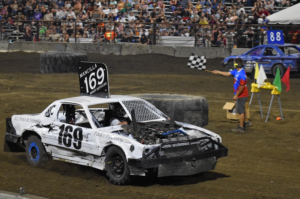 A car passes the finish line with the checkered flag waving at the Agri-Service Demolition Derby on Aug. 16.